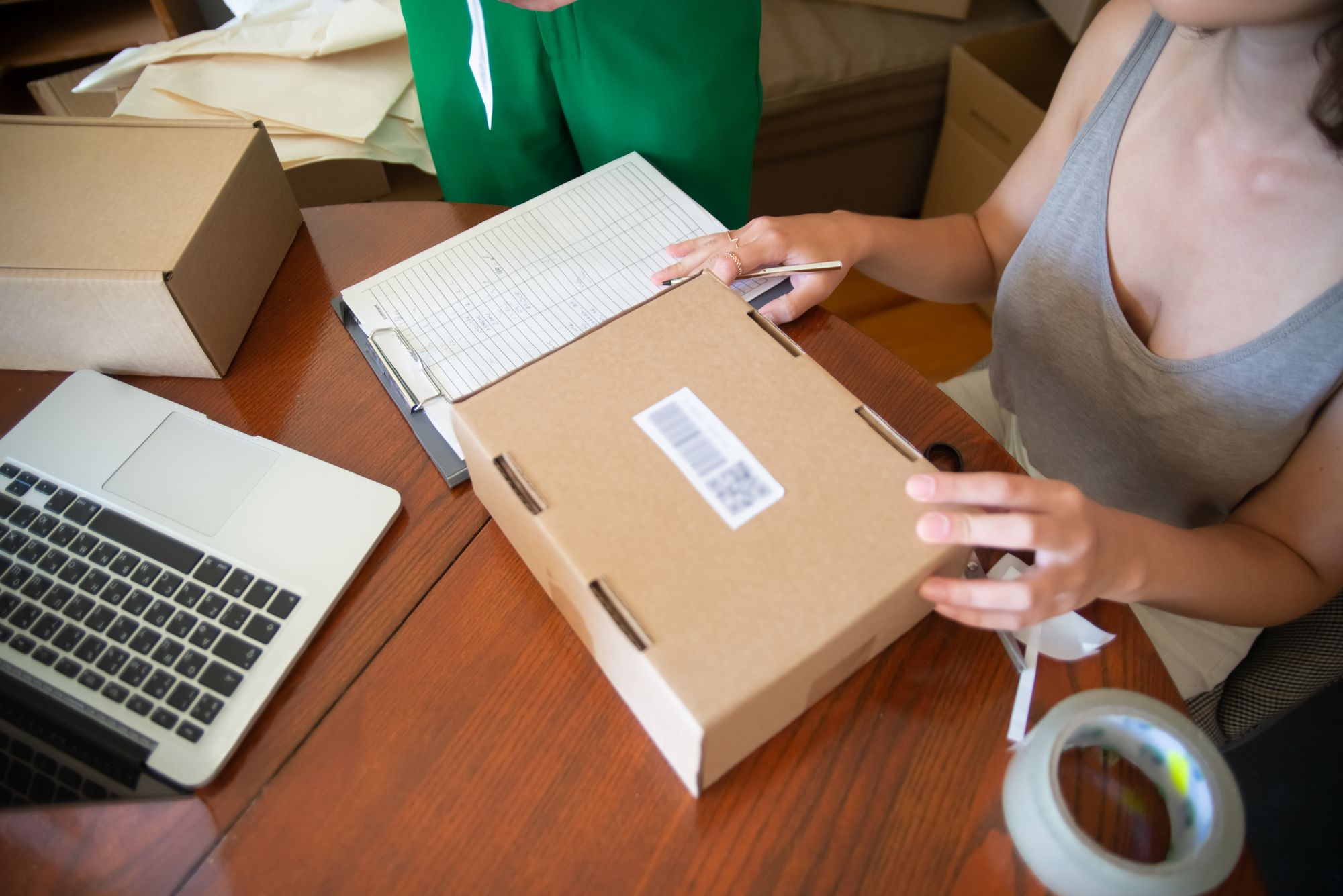 Ecommerce order checking and parcel preparation beside a laptop