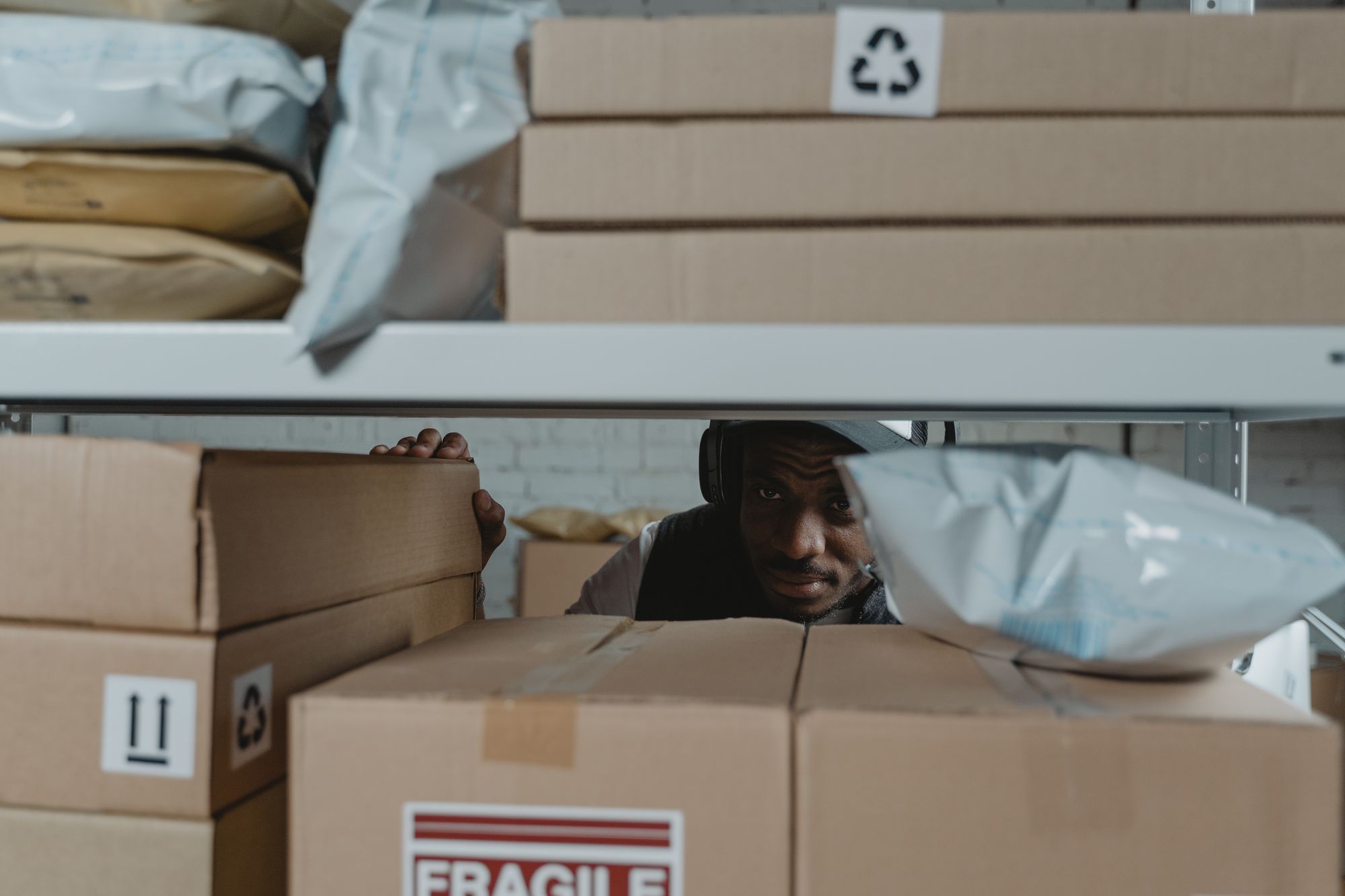 Warehouse worker checking parcels on a storage shelf