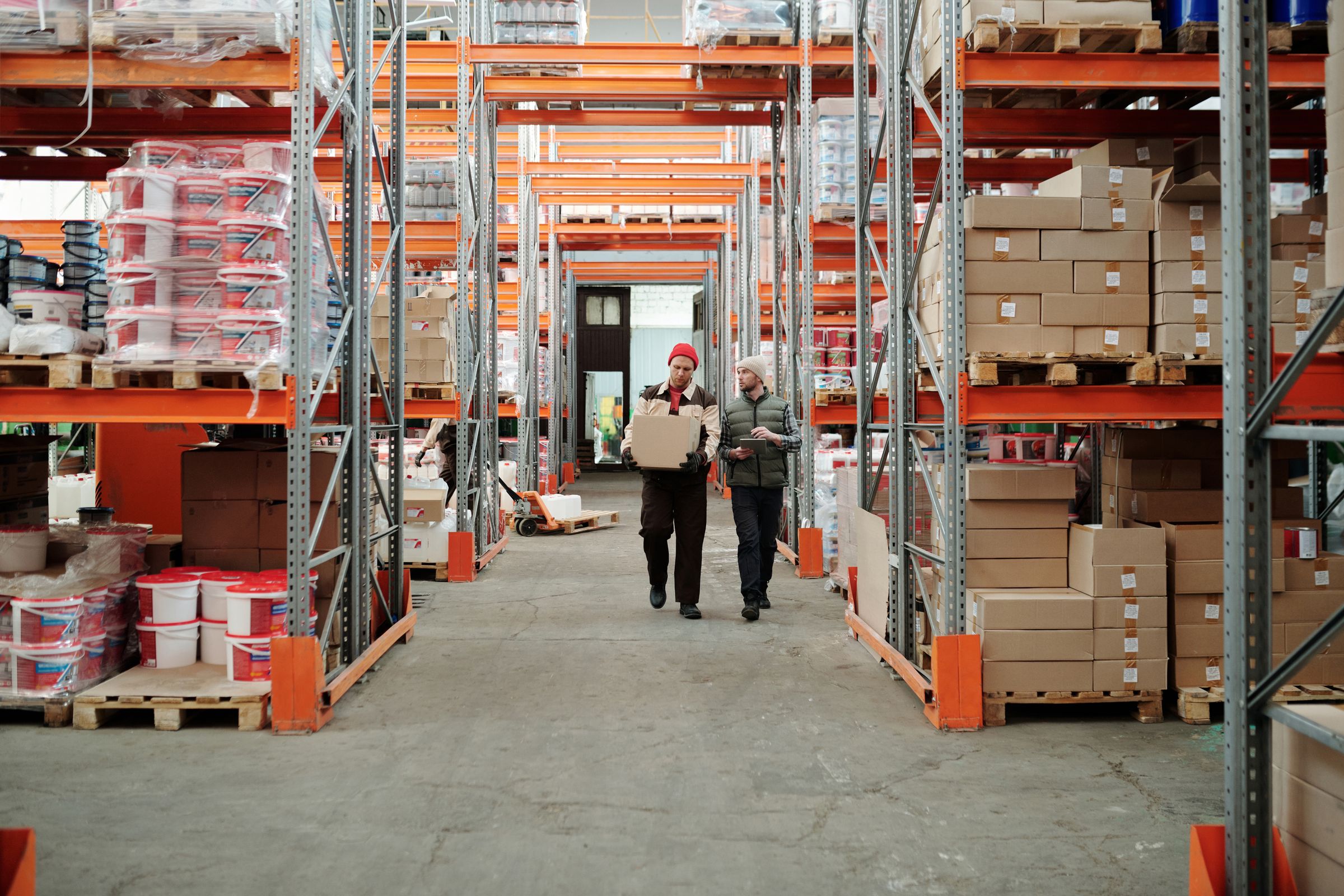 Warehouse staff checking a carton in a storage aisle