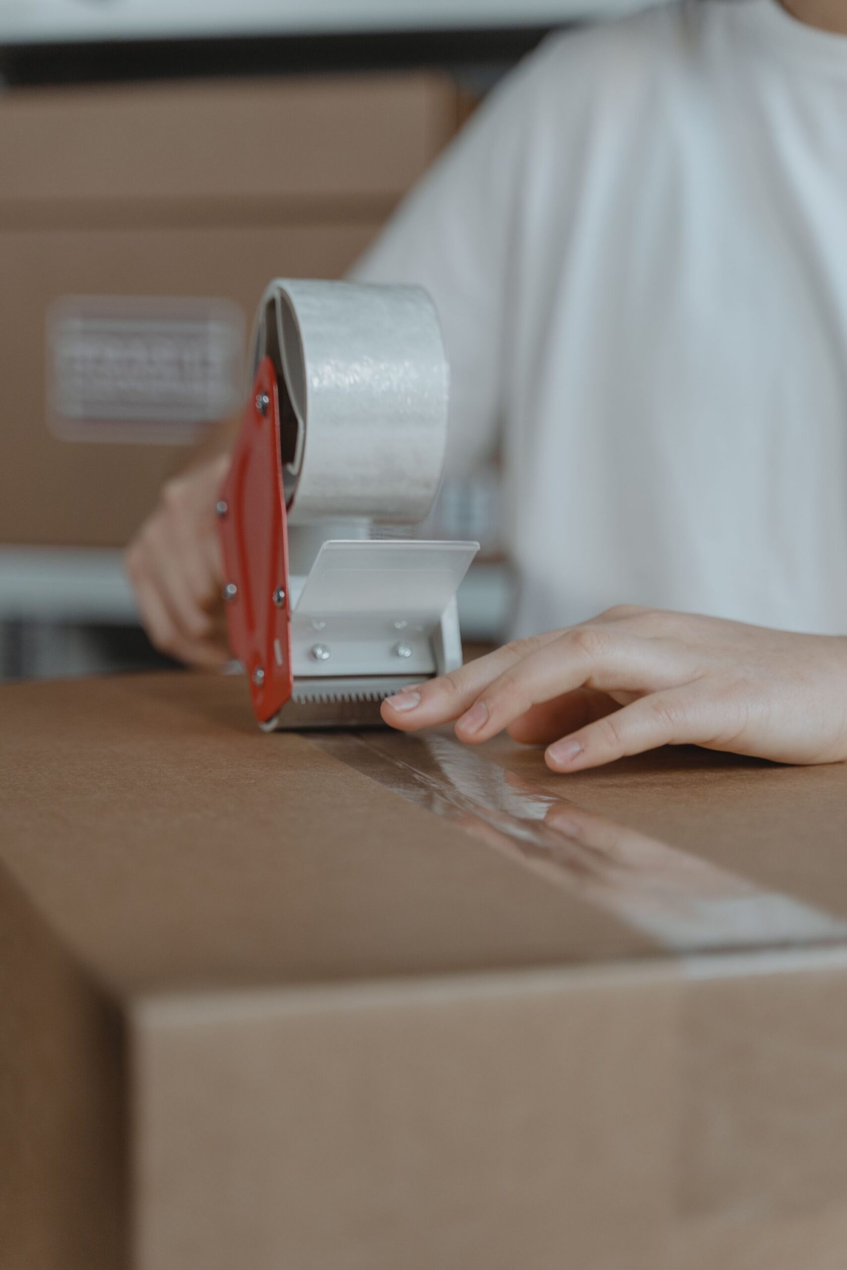 Hands securing a packed parcel with a tape dispenser